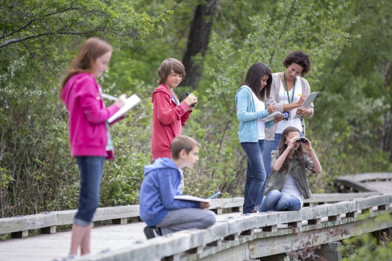 Junior high students and teacher taking notes on outdoor field trip